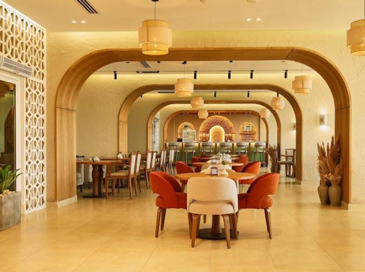 A spacious dining area with high wooden arches, multiple dining tables, and hanging pendant lights.