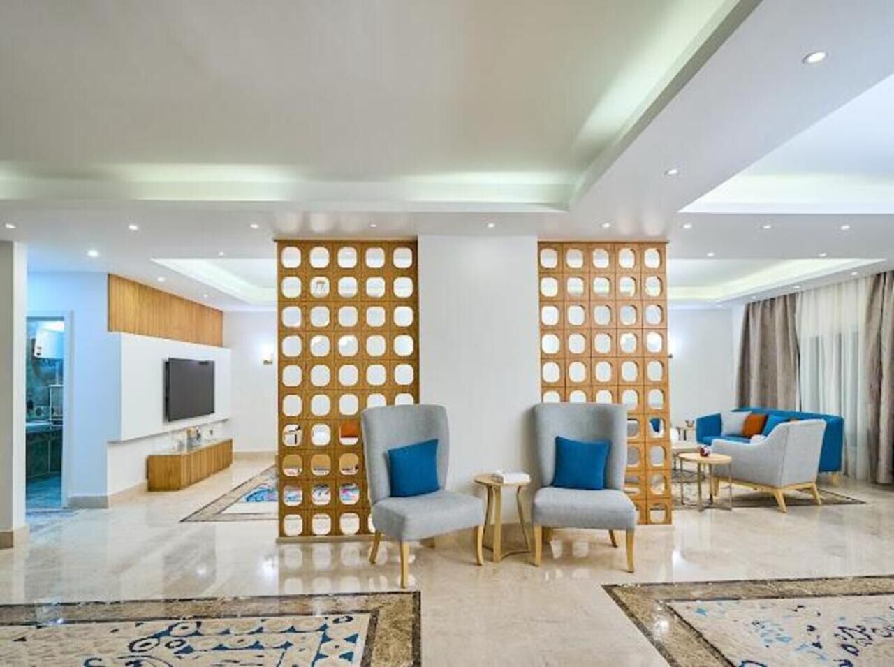 A modern living room with a TV, two armchairs, a sofa, and a decorative wooden partition.