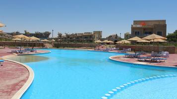 A swimming pool with multiple lanes, lounge chairs, and umbrellas.