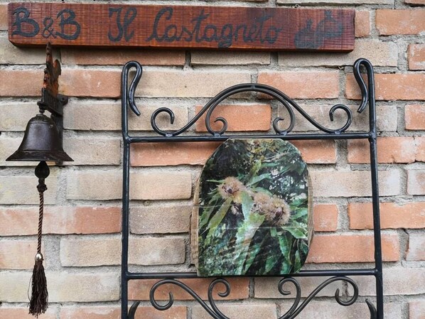 Un mur de briques sur lequel est fixée une enseigne en bois indiquant « B&B El Cartoneto ».