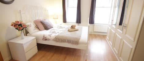 A bedroom with a bed, nightstand, and a clock on the wall.