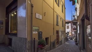 Une ruelle étroite pavée, bordée de bâtiments des deux côtés. On peut voir une enseigne indiquant « SALITA MELLA » sur le bâtiment jaune.