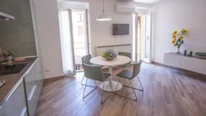 Une cuisine moderne dotée d’une cuisinière intégrée, d’un coin repas avec une table ronde et quatre chaises, et d’une grande fenêtre qui laisse entrer la lumière naturelle.
