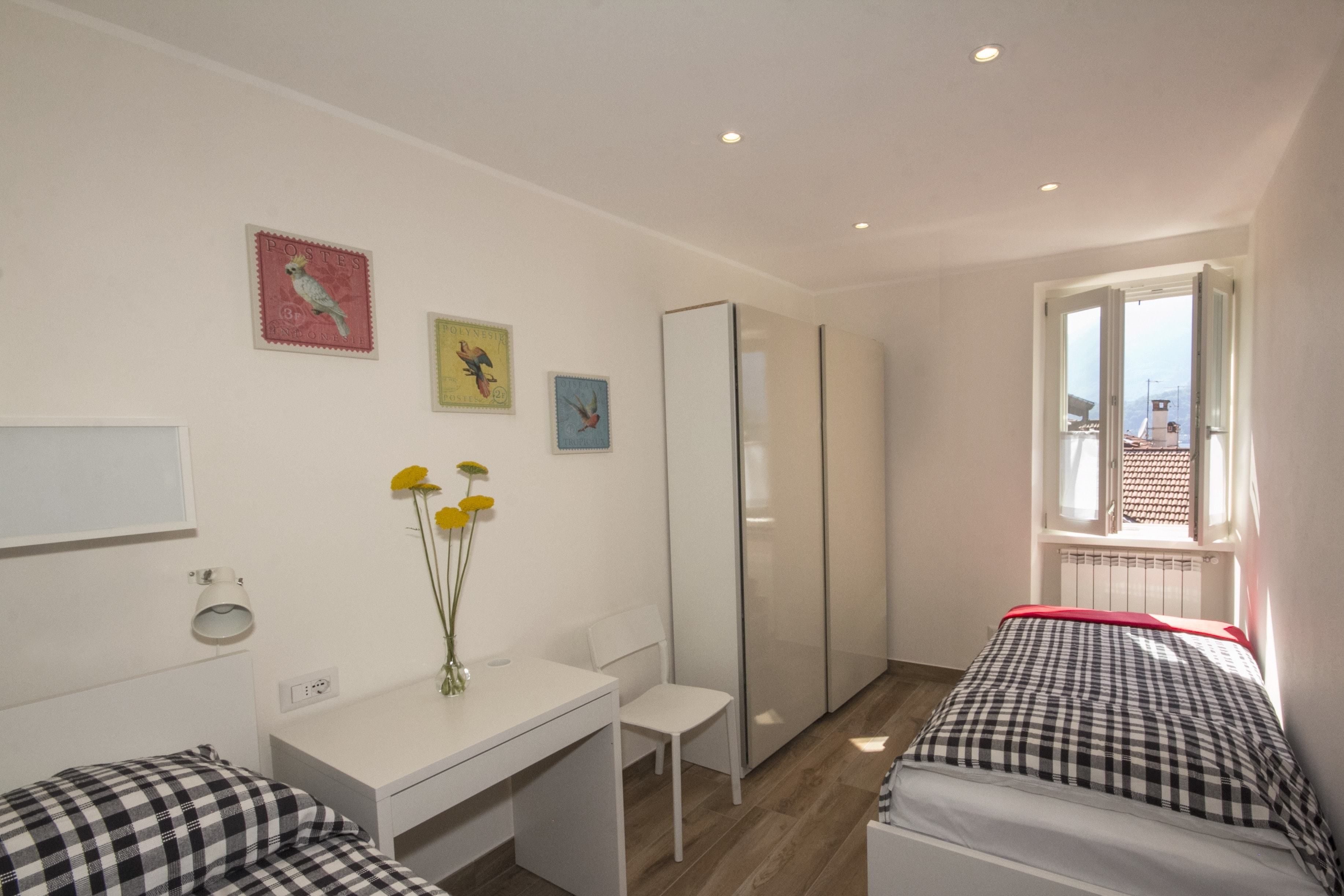 Une chambre à coucher comprenant un lit, un bureau, une chaise et une fenêtre donnant sur l’extérieur.