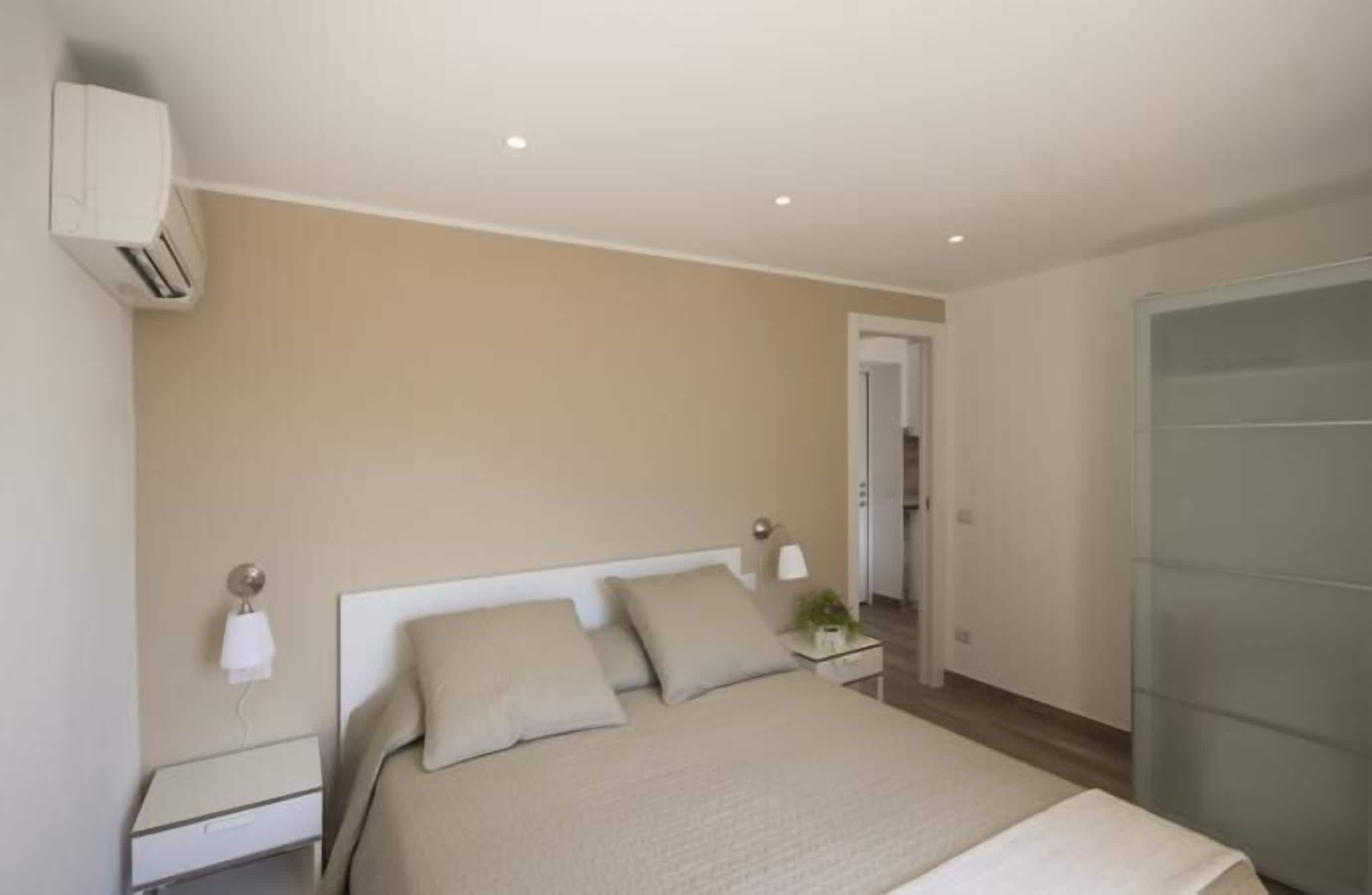 Un dormitorio moderno con cama, mesitas de noche, lámpara y armario.