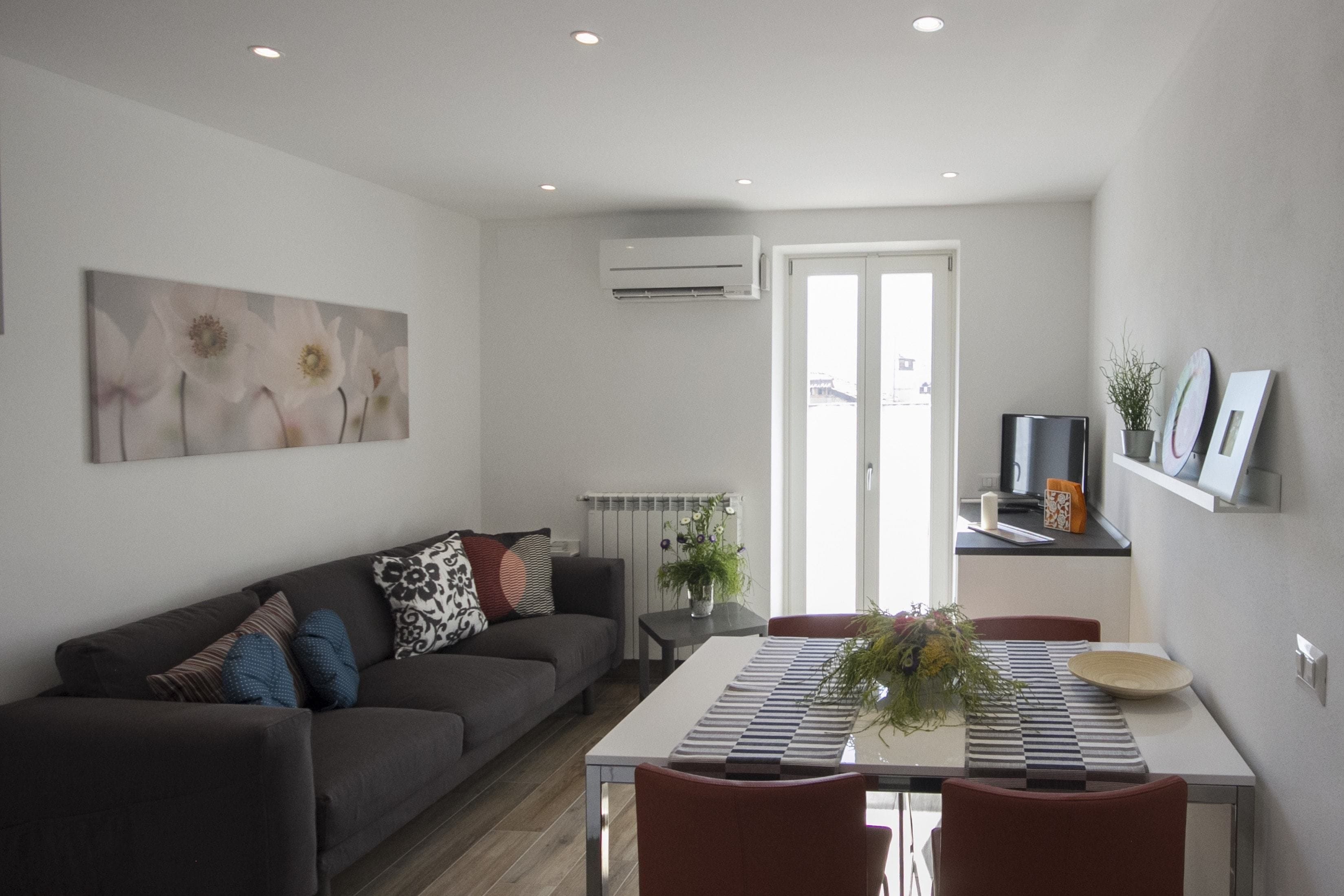 Uma sala moderna com sofá, mesa de jantar e área de cozinha.