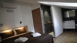 A hotel room with a bed, a bathroom, and a shower area. - Suites in Erbalunga (Brando)