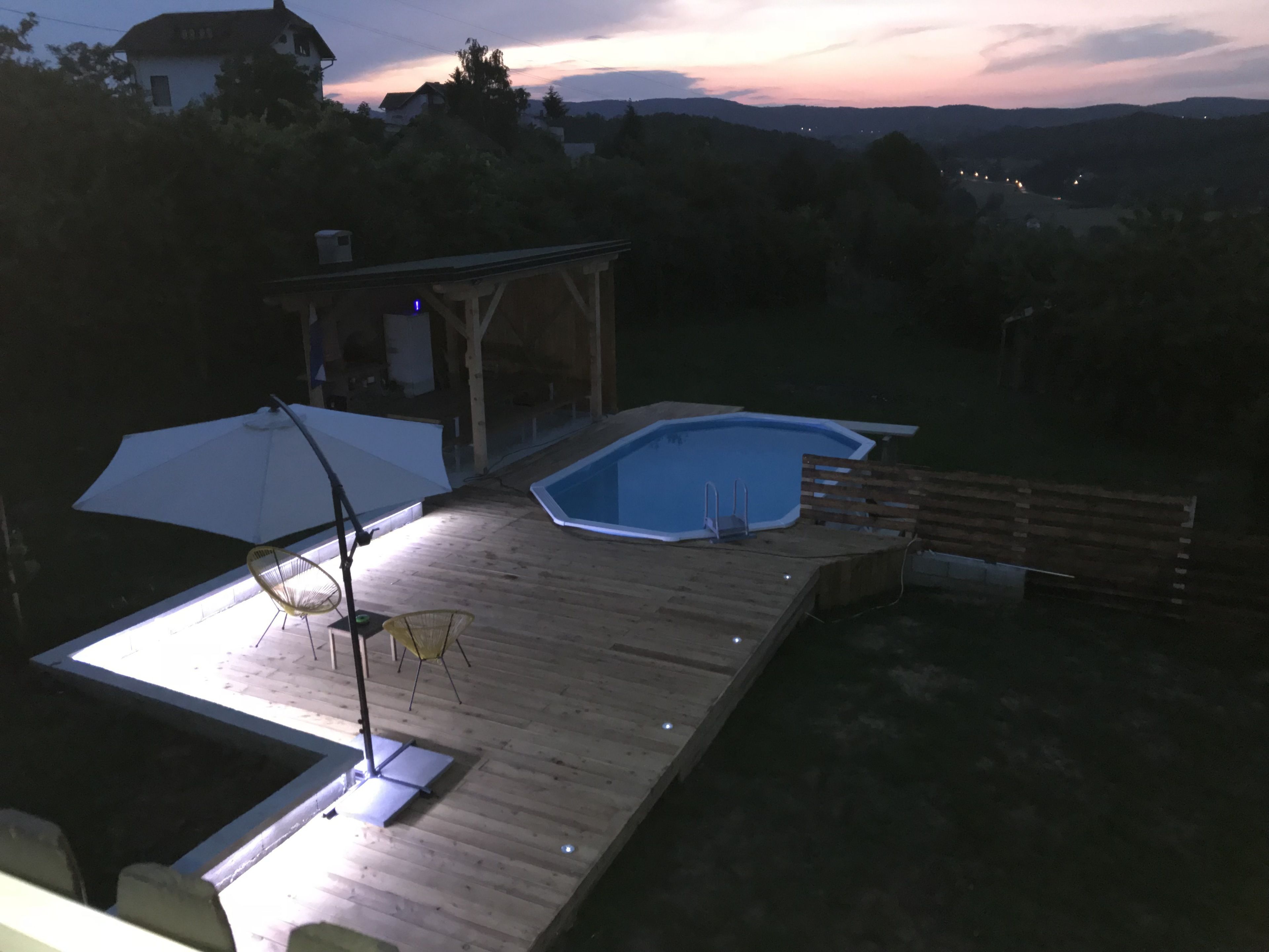 Een houten terras met een jacuzzi, een overdekte zithoek en uitzicht op het omliggende landschap.