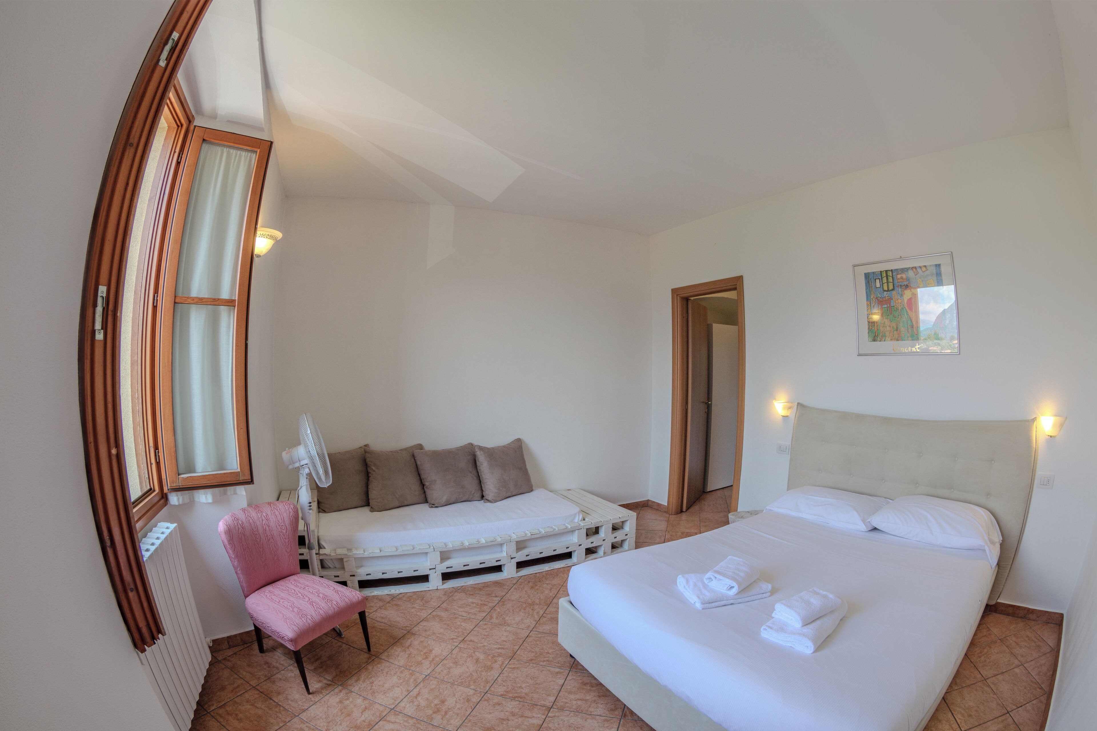A bedroom with a bed, a chair, a small table, and a window.