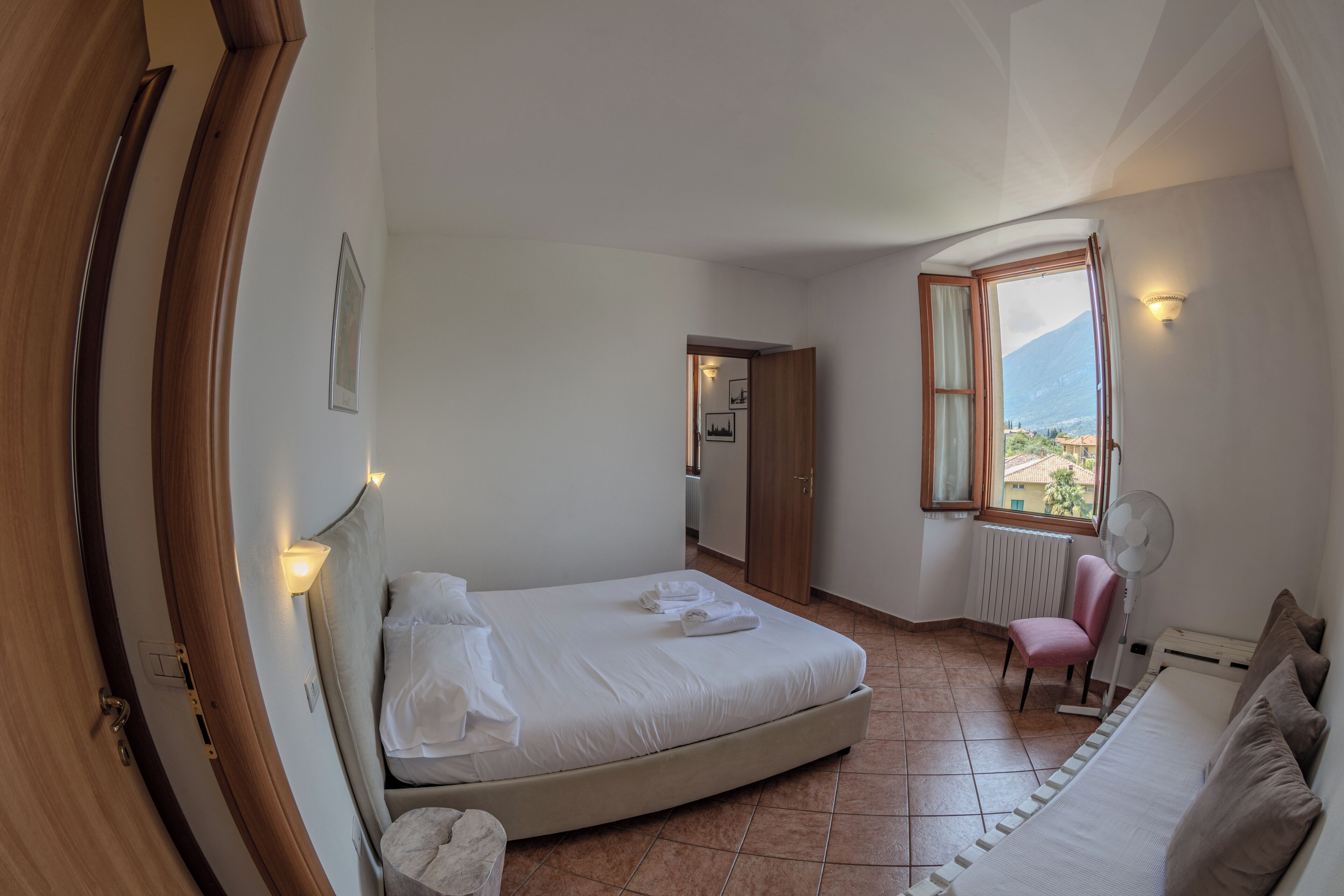 Un dormitorio con una cama, una silla, un ventanal con vistas y una puerta.