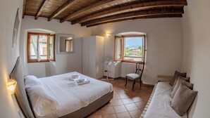 Une chambre à coucher comprenant un lit, une chaise, un canapé, une fenêtre avec vue et un plafond en bois.