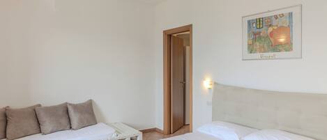 A bedroom with a bed, a sofa, and a door.