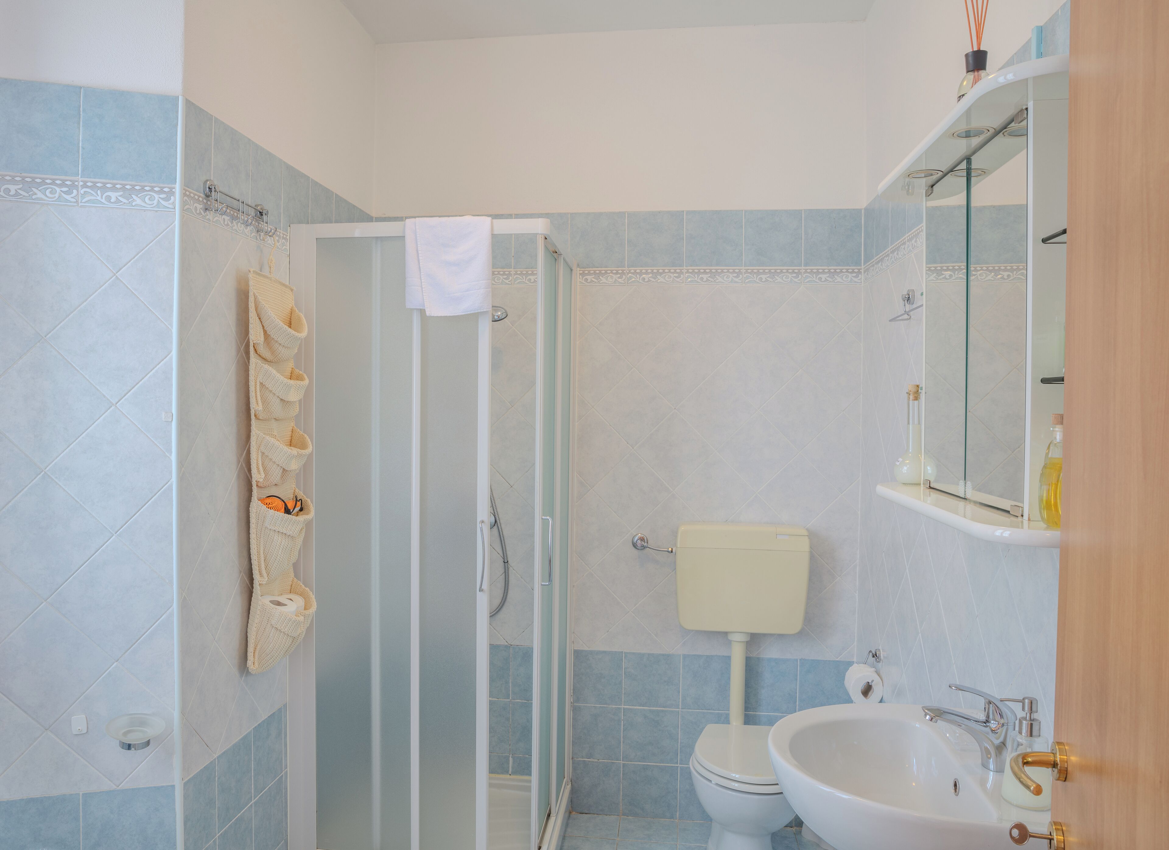 Een badkamer met een douchecabine van glas, een toilet en een wastafel met een spiegel erboven.