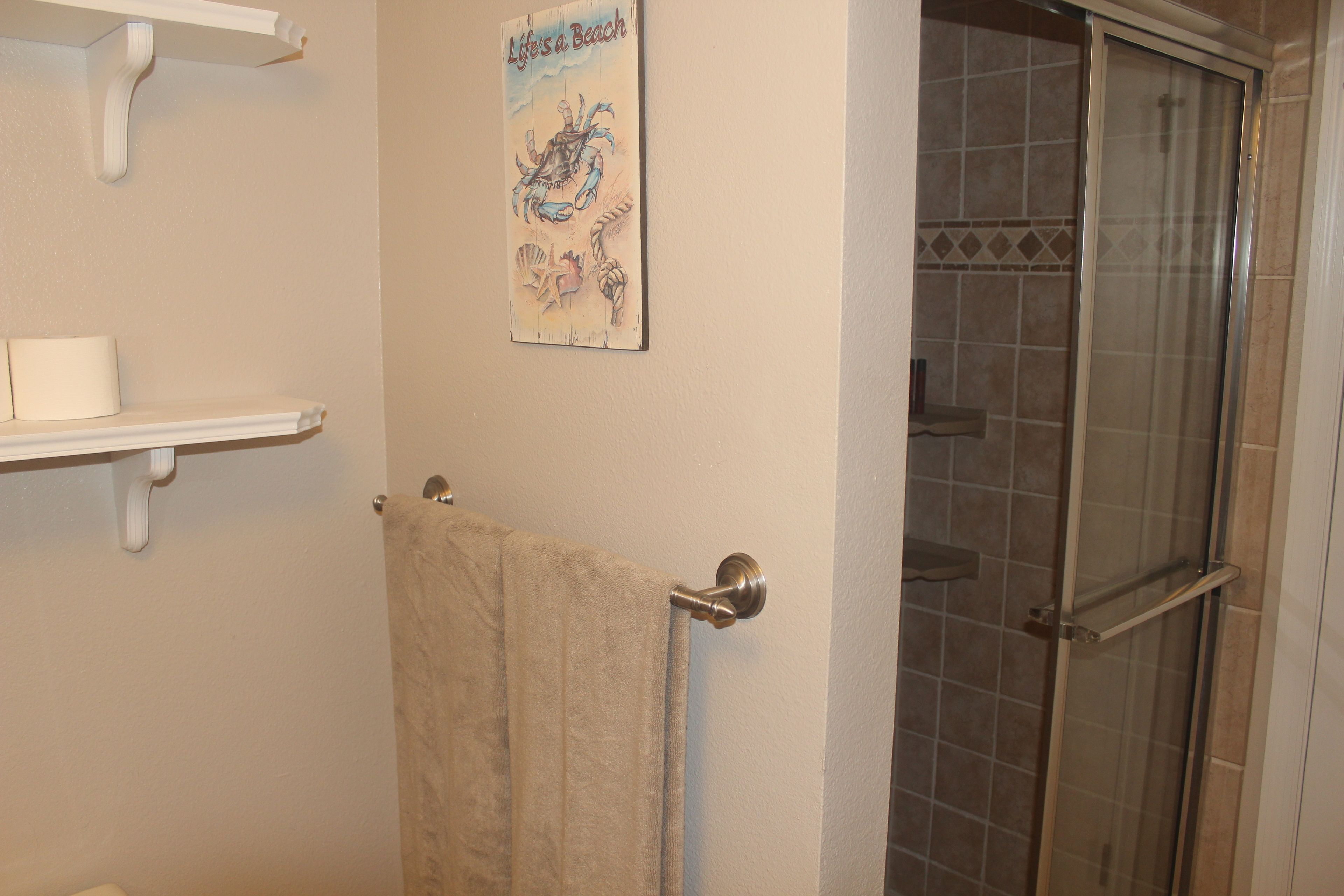 Ein Badezimmer mit Dusche, Handtuchhalter und Ablage mit Handtuch.