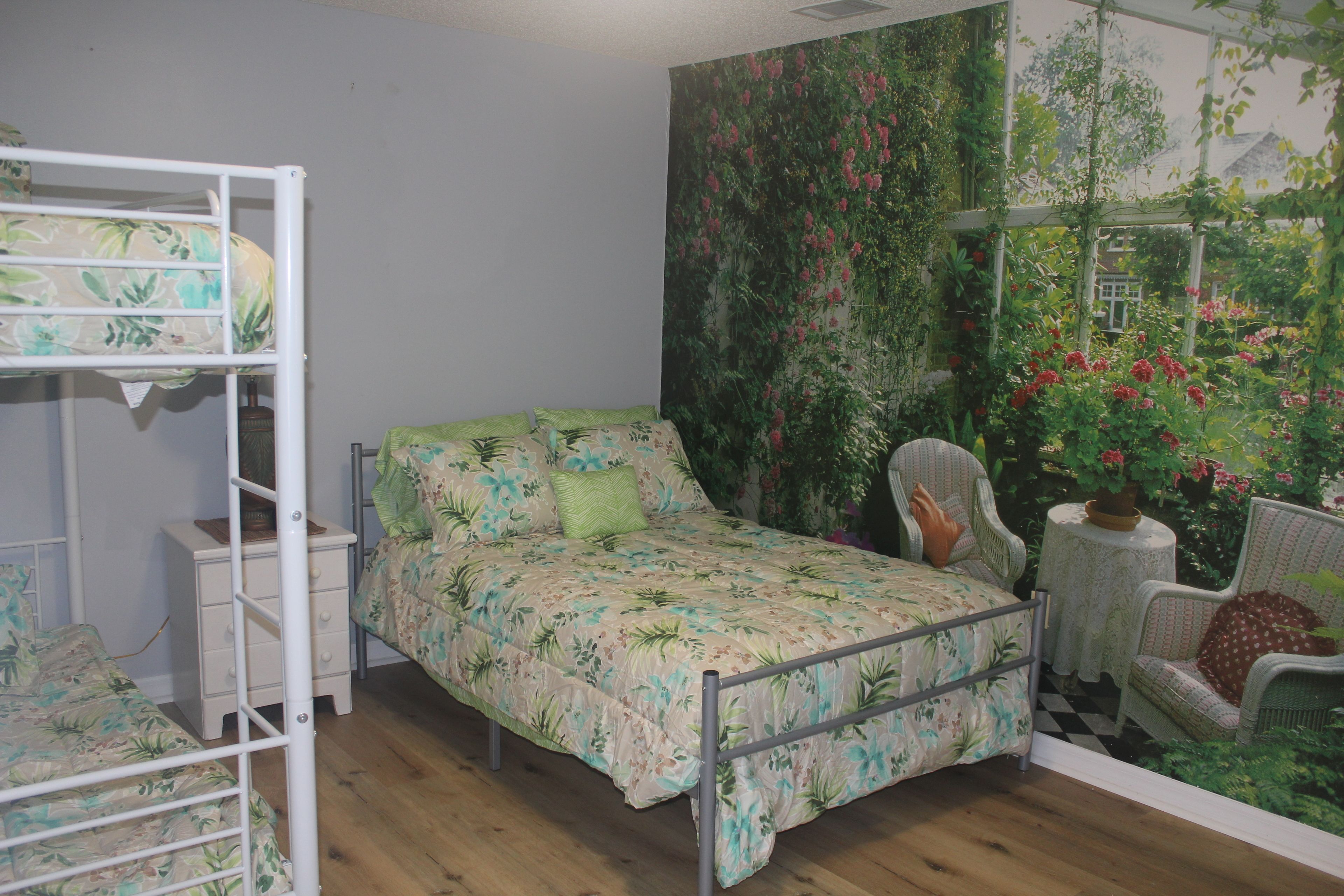 A bedroom with a bunk bed, a single bed, and a chair.