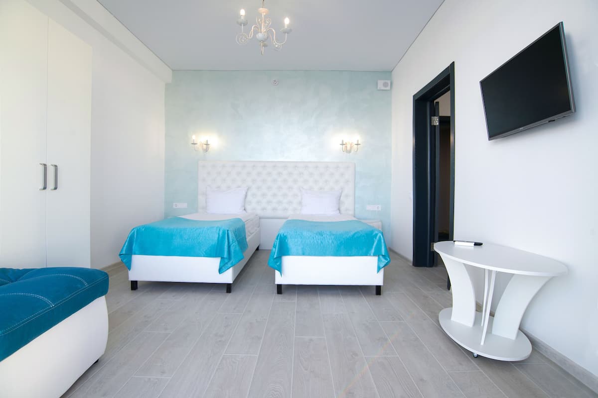 A bedroom with two beds, a white table, and a TV on the wall.