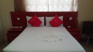 Una cama bien hecha con una colcha blanca y dos almohadas rojas.