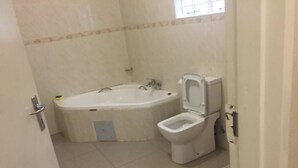 Un baño con bañera, inodoro y zona de ducha.