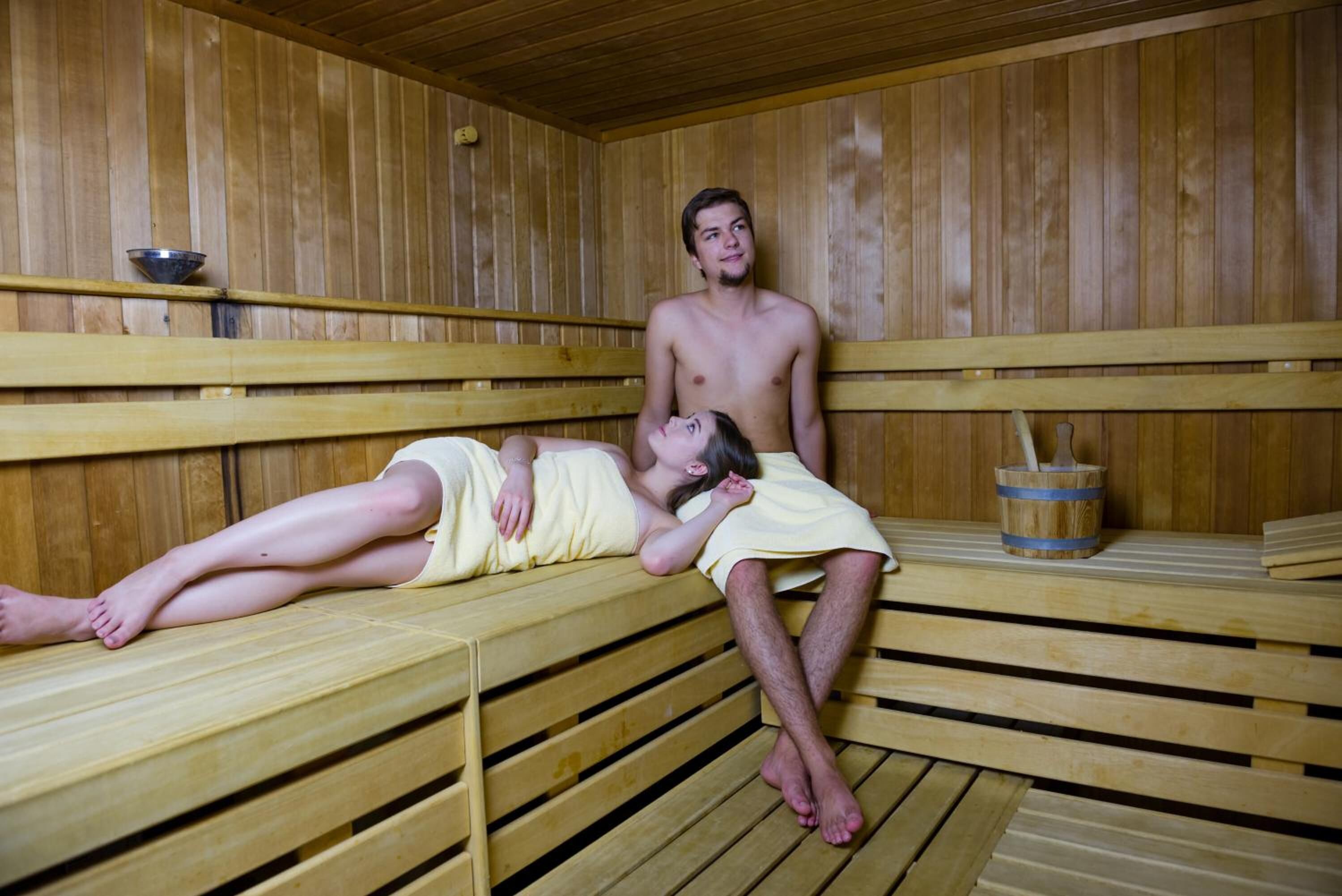 A sauna with wooden benches and a wooden bucket with a brush.