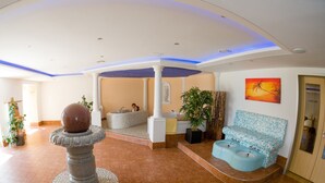 A spacious lobby with a central fountain, a seating area with a patterned sofa, and a large painting on the wall. - Landhotel Aschenbrenner (Freudenberg)