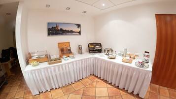 Ein Buffet mit verschiedenen Speisen und Getränken, ein Stadtbildgemälde an der Wand und eine Holztür.