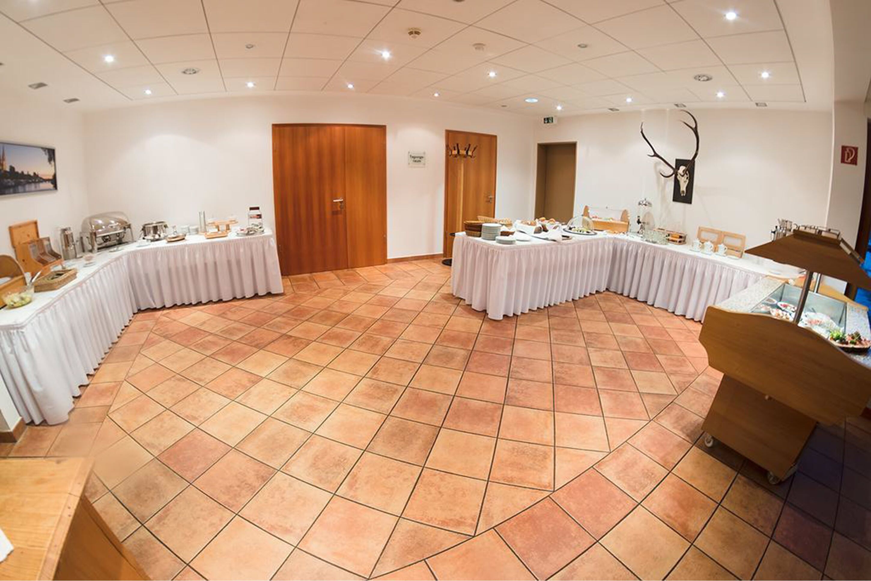 Een congreszaal met een gebogen tafel, een houten deur en een aan de muur bevestigd hertenhoofd.