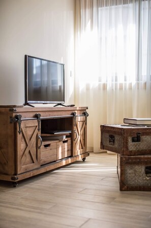 Uma estante de madeira com televisão de tela plana, gavetas e uma mala.