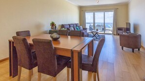 Una sala de estar moderna con una mesa de comedor, sofás y un balcón con vistas.