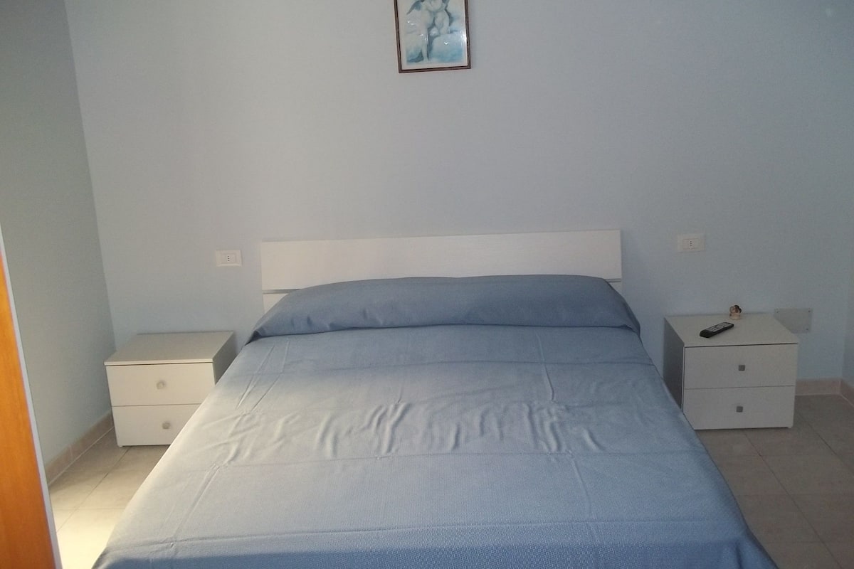 Een slaapkamer met een eenpersoonsbed, twee nachtkastjes en een nachtkastje.