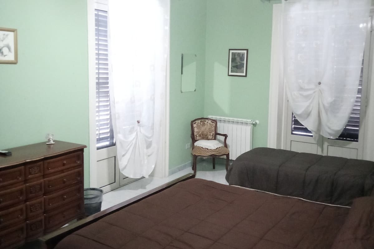 Een slaapkamer met een groot bed, een kapstok, een stoel en een radiator.
