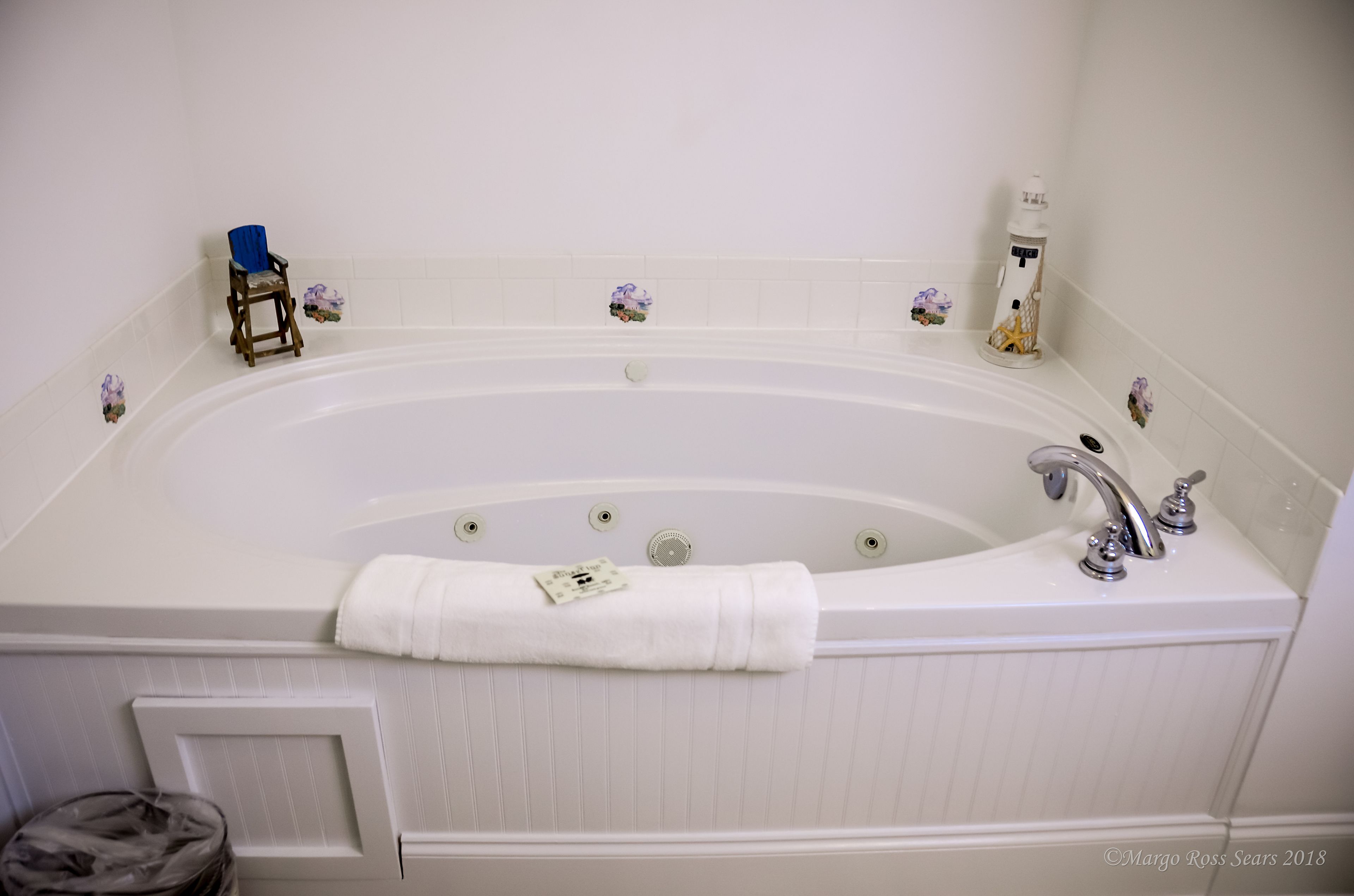 A large, white freestanding bathtub with a single faucet and a towel draped over the side.