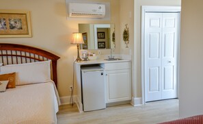 Un dormitorio con cama, mesita de noche, lámpara y un refrigerador pequeño.