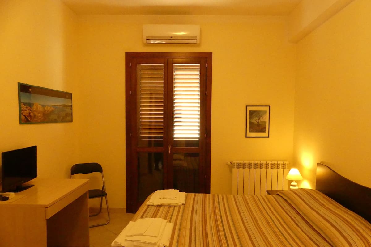 Ein Hotelzimmer mit Bett, Schreibtisch, Stuhl, Klimaanlage und Heizkörper.