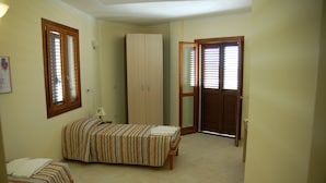 Une chambre avec deux lits, une armoire et une porte donnant sur une autre pièce.