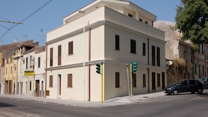 Un immeuble d’angle à la façade plate, doté de nombreuses fenêtres et d’une enseigne visible donnant sur la rue.