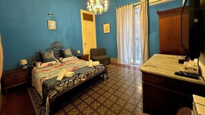 Une chambre à coucher comprenant un lit, une chaise, un bureau, un téléviseur et un lustre.