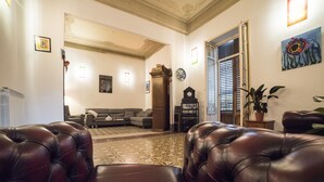 Un salon avec des canapés en cuir, un tapis à motifs, une horloge et une porte qui donne sur une autre pièce.
