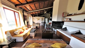 Amplia sala de estar con techo alto, un conjunto de sofás, una mesa de comedor y una chimenea.