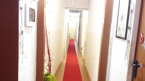 A hallway with a red carpet, wooden floors, and white walls. - Affittacamere Maristella (Cagliari)