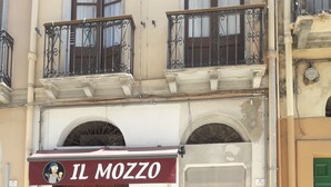 A building with a sign reading "IL MOZZO" above a wooden door. - Affittacamere Maristella (Cagliari)