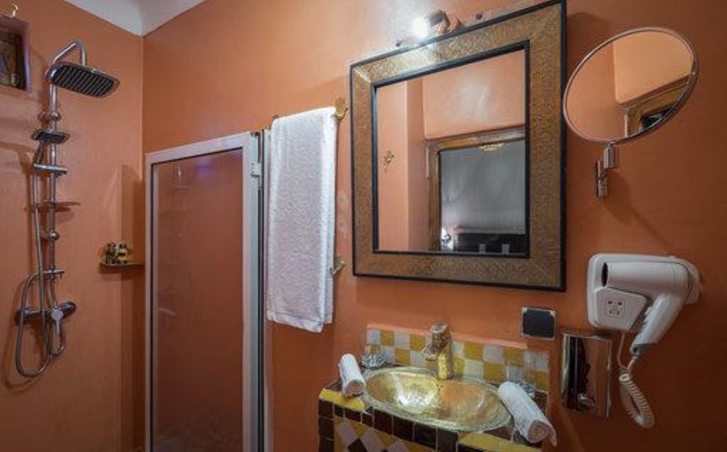 Un baño con ducha, lavabo, espejo y secador de pelo.