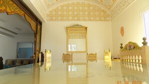 A room with a high ceiling featuring intricate geometric patterns, a large mirror, and a decorative wooden headboard. - House Dar Mamina (Zarzis)