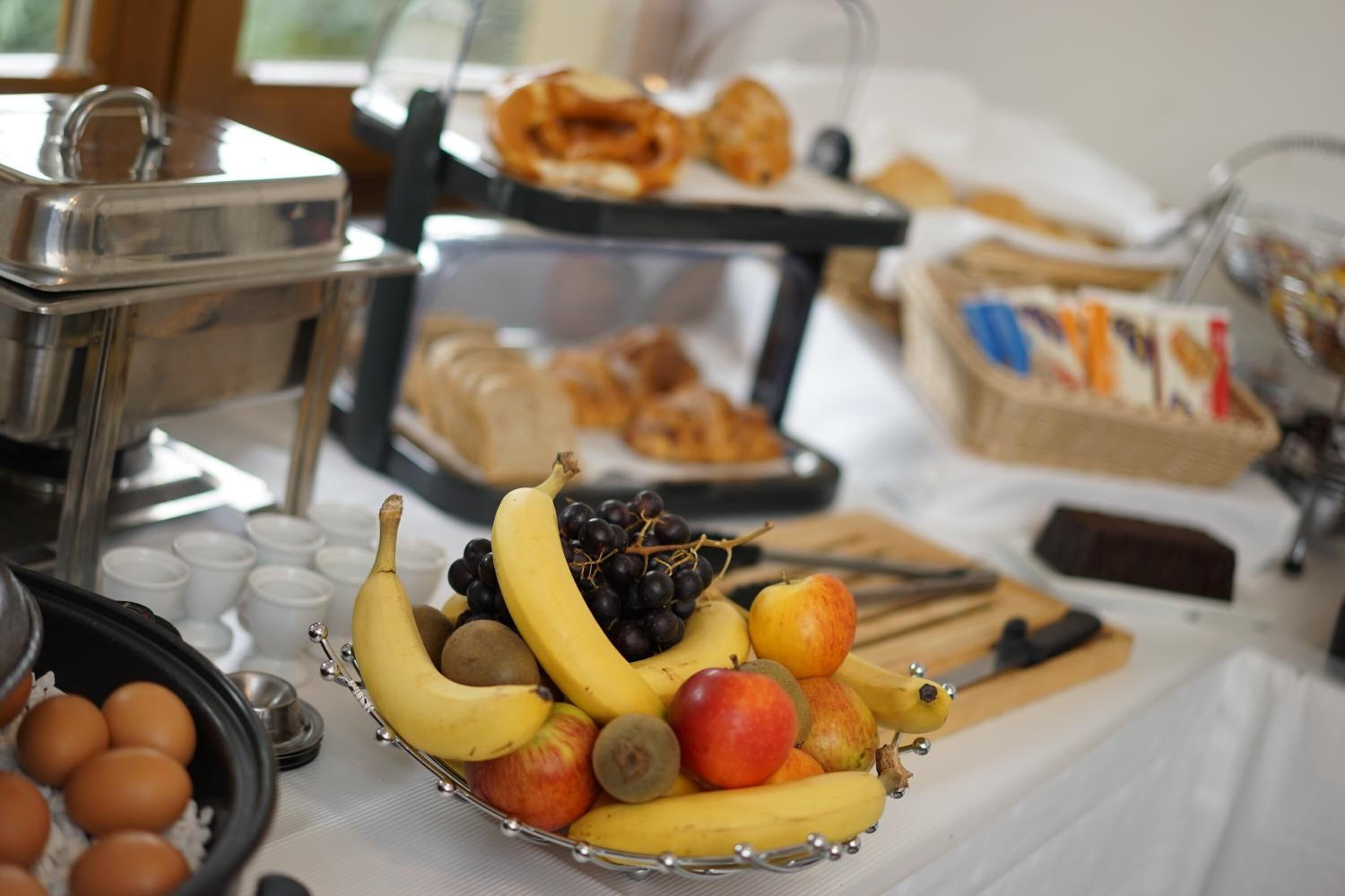 A buffet table with various food items including fruits, eggs, and pastries.