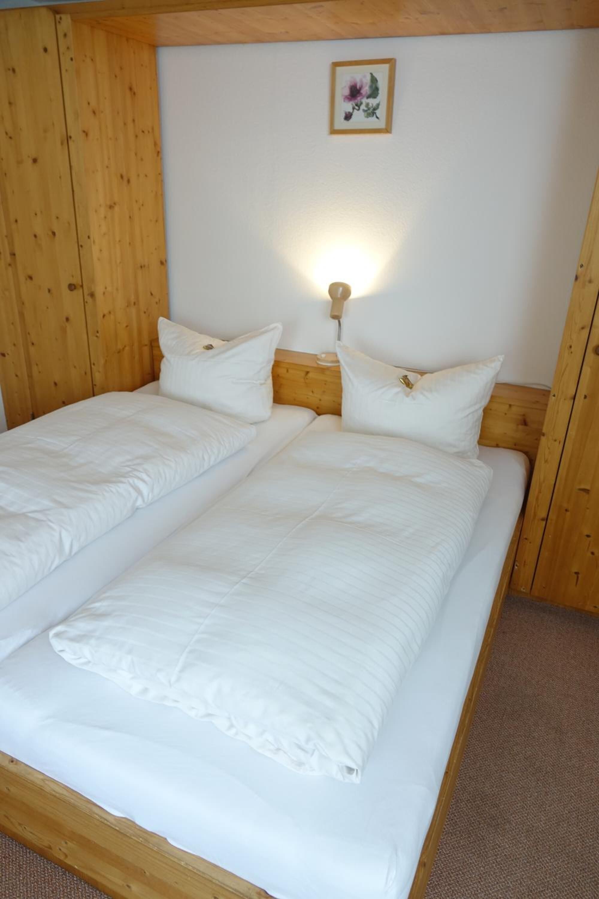 A double bed with white bedding and a wooden headboard in a room with wooden paneling.