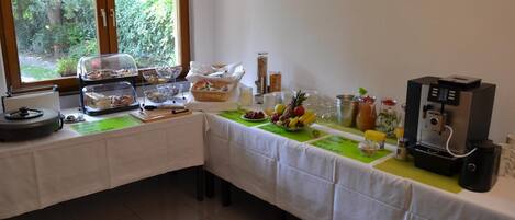 Montaje de un bufé de desayuno con diversas opciones de comida y una máquina de café.