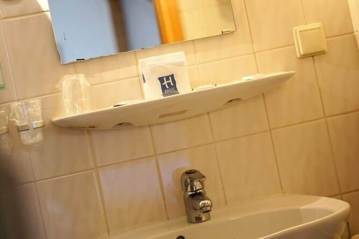 Uma casa de banho com uma pia branca, um espelho e uma toalha pendurada na parede.