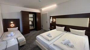 Ein Hotelzimmer mit zwei Betten, einem Schreibtisch, einem Spiegel und einem durchgegangene Tür sichtbaren Badezimmer.