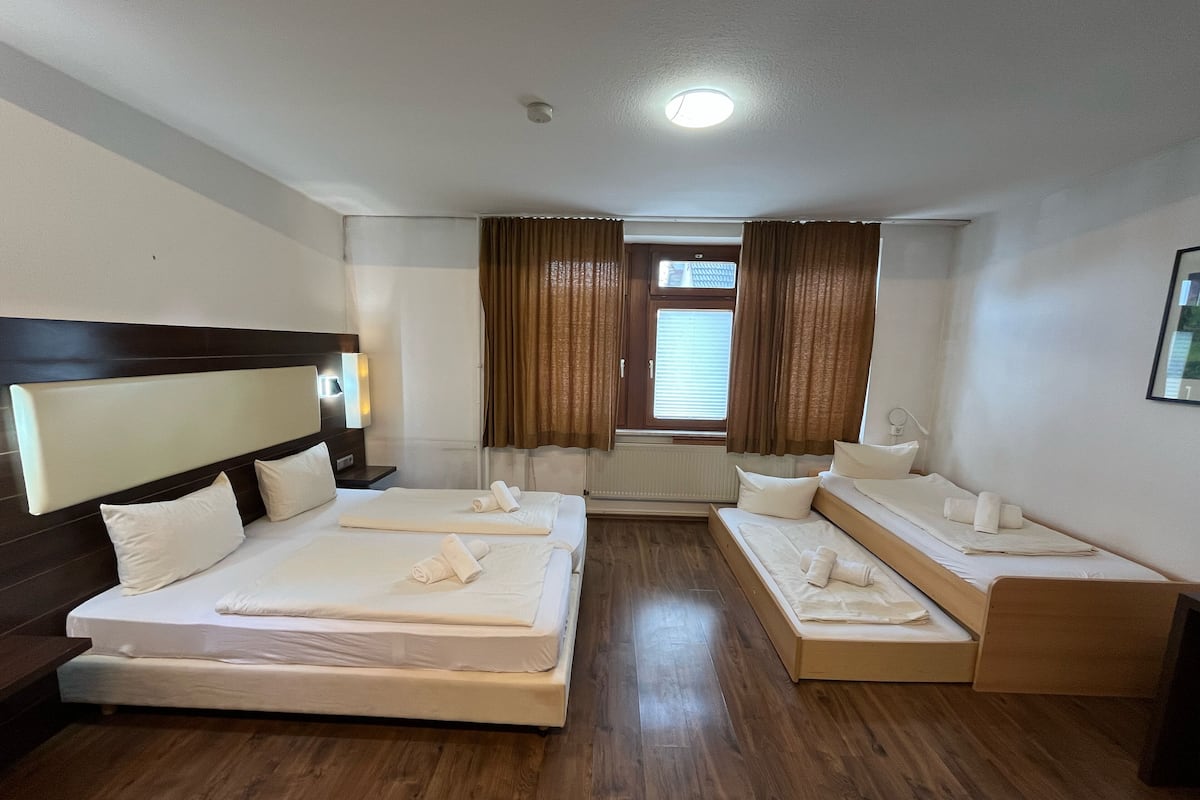 Quarto de hotel com duas camas, um espelho grande, uma janela com cortinas e uma luminária no teto.