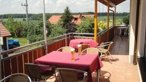 A balcony with a table and chairs, a beer on the table, and a view of the countryside. - Landgasthof Metzgerei Traube (Heidenheim an der Brenz)