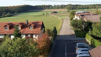 Eine Wohnstraße mit Häusern an beiden Seiten, parkenden Autos und freiem Blick ins Grüne.